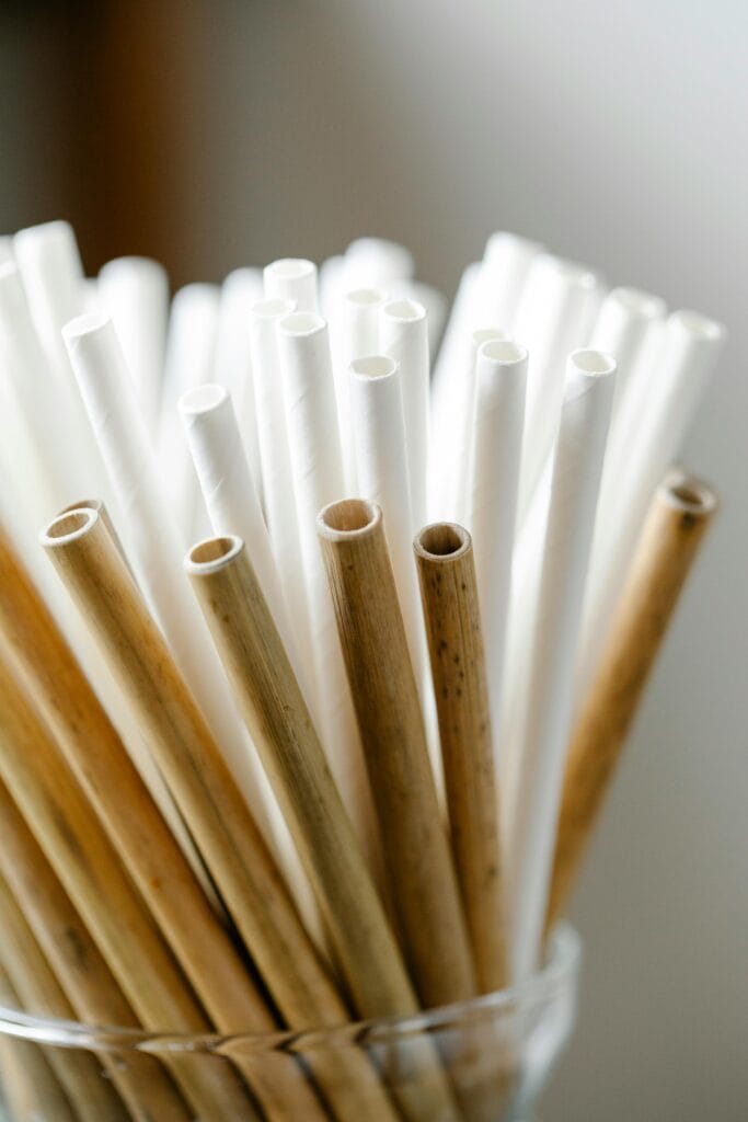 Close-up of eco-friendly bamboo and paper straws arranged in a glass container, promoting sustainable living.